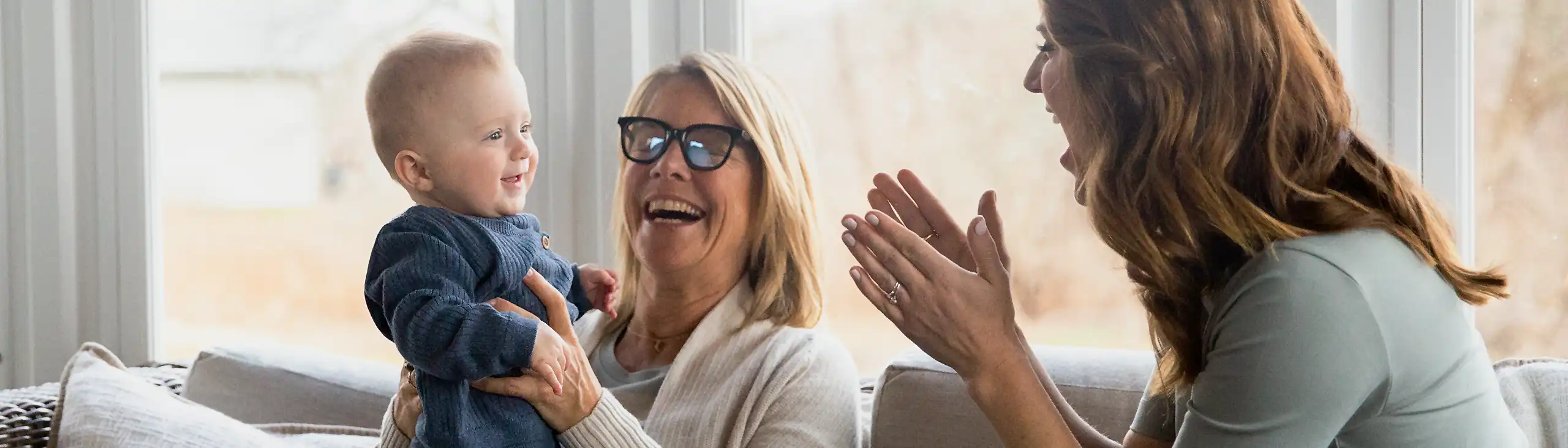 Parent, grandparent, and infant smiling and playing