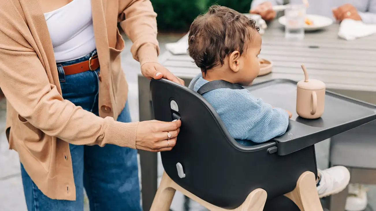 A parent adjust the harness on the back of the high chair